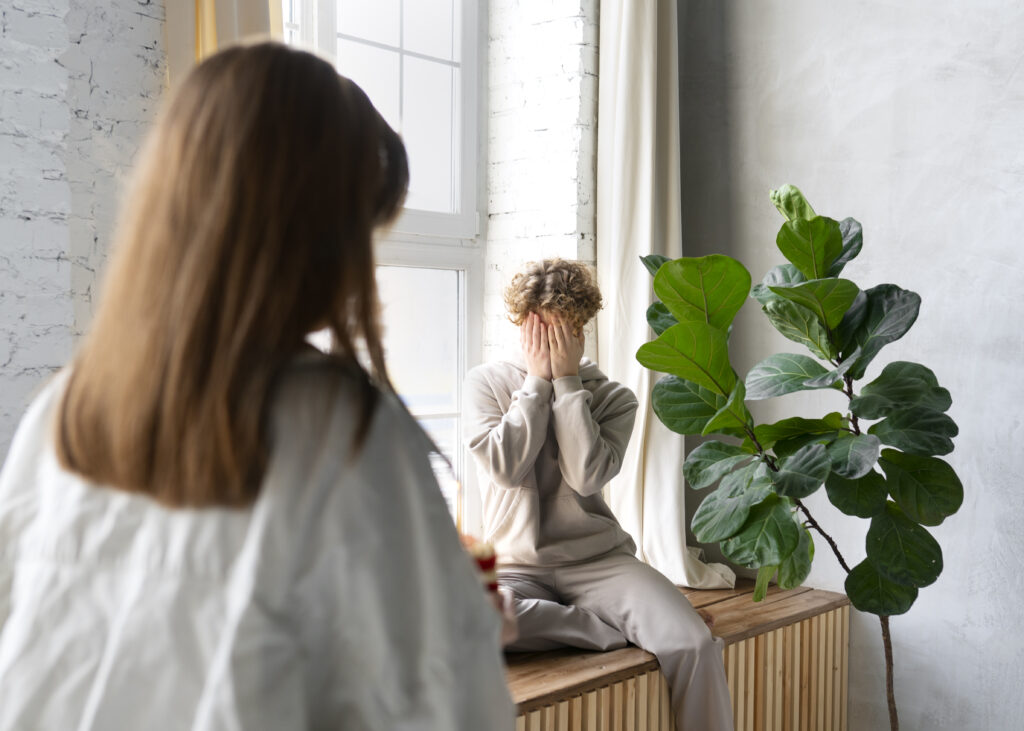 Chico tapándose la cara debido a un ataque de pánico, buscando alivio con terapia.